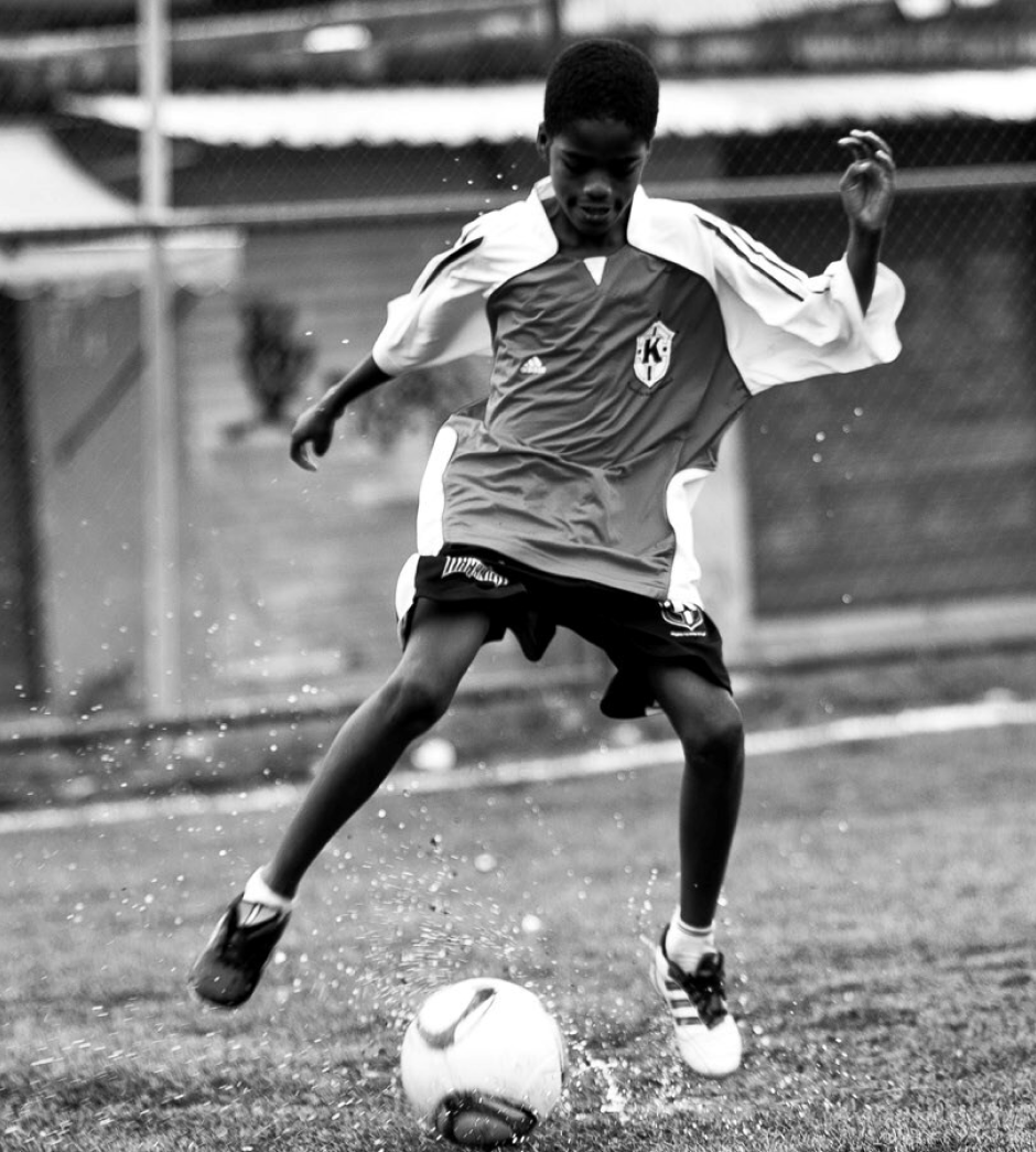 child in karanba uniform kicking a football